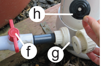 the different parts of the RainWise low flow drainage system: the valve, orifice housing, and orifice. The valve is a red, plastic tab. The orifice housing is a plastic coupler with ridges. The orifice is a black rubber circle that fits inside the coupler. It has a small hole in the center.  